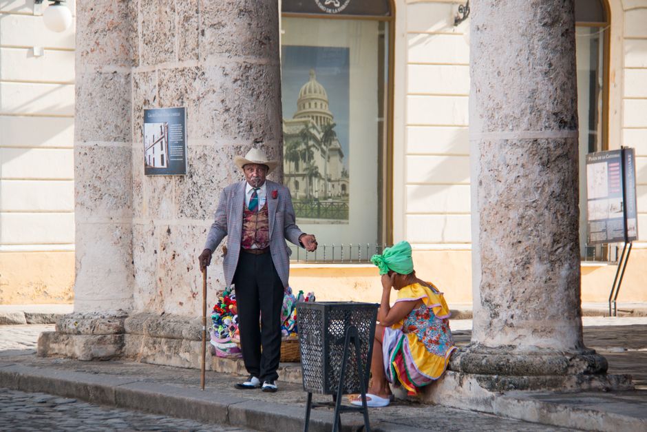 Street vendors in colorful attire near the iconic Plaza Vieja in Havana, Cuba.