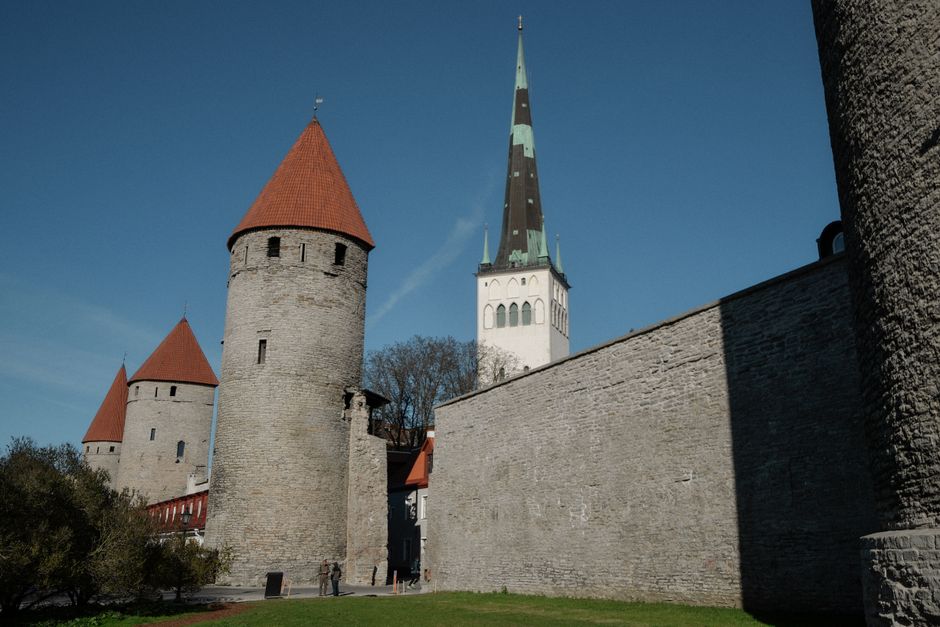 Medieval stone towers and St Olaf's Church under a blue sky in Tallinn, Estonia.